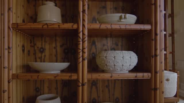Wooden shelving unit displaying ceramic bowls and pottery AI video preview